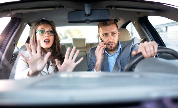 Girl panicking in the car as her boyfriend drives and talks on the phone in the same time - Foto, imagen