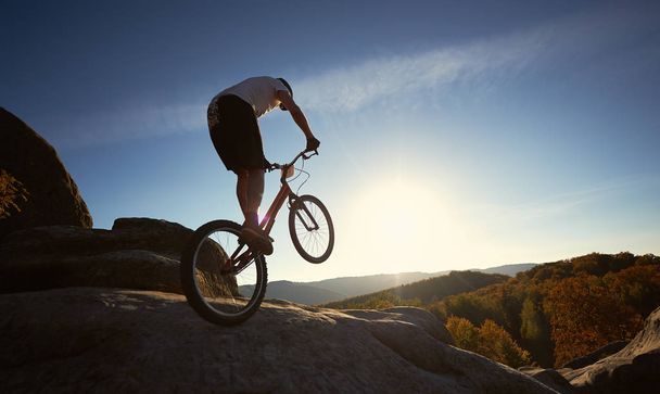 silhueta de atleta ciclista balanceamento na roda traseira na bicicleta de teste
 - Foto, Imagem