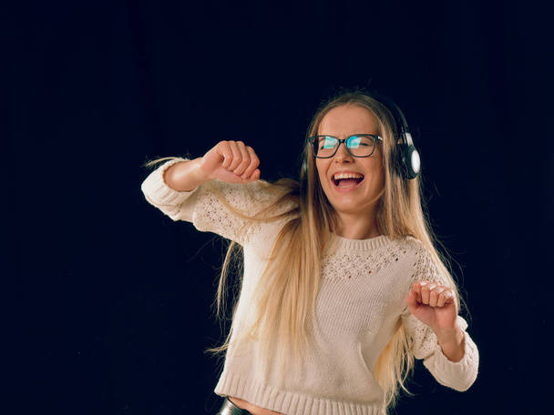 schöne junge Frau genießt die Musik in drahtlosem Kopfhörer auf dunkelschwarzem Hintergrund - Foto, Bild
