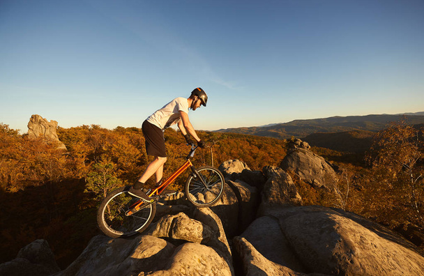 Спортсмен-велогонщик балансирует на заднем колесе на пробном велосипеде
 - Фото, изображение