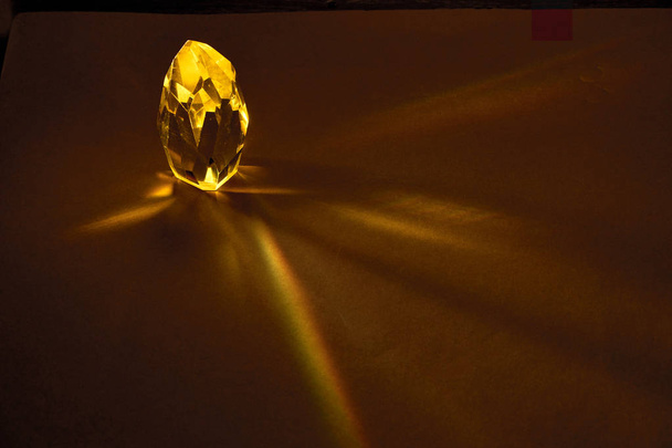Промені світла, що проходять через великий жовтий кварцовий кристал на темно-коричневому тлі
. - Фото, зображення