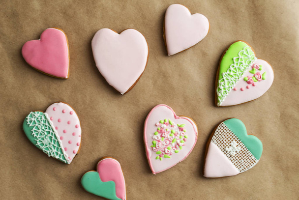 Gingerbread gingerbread in pink glaze, on craft background. Bakery products. Gingerbread in the shape of a heart. Place for text. Gingerbread pattern Background. - Zdjęcie, obraz
