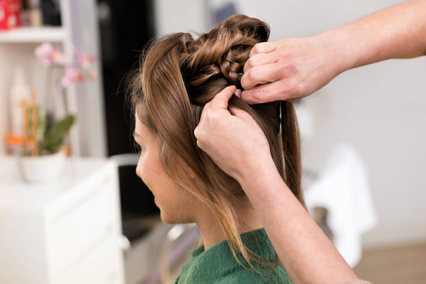 Close-up de cabeleireiros profissionais mãos durante a pentear um corte de cabelo criativo para menina morena no salão de beleza, visto do lado
 - Foto, Imagem