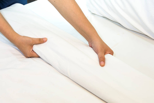 Hand set up white bed sheet in bedroom - Photo, Image