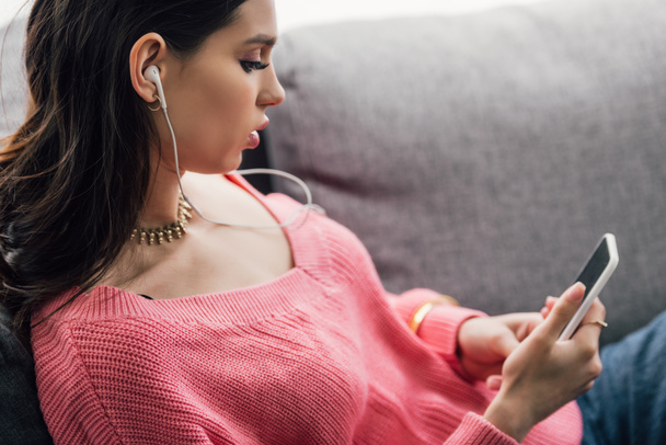 attractive indian woman listening music with earphones and using smartphone - Photo, Image