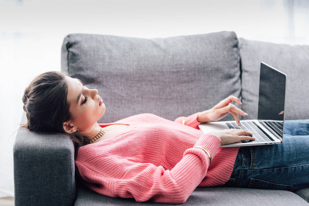 indian woman using laptop with blank screen while lying on sofa - Foto, Bild