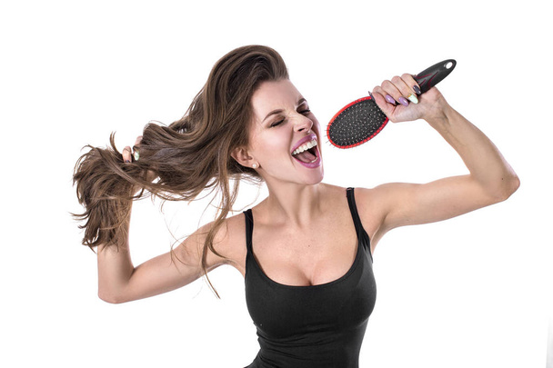 Emotional girl singing in hairbrush on white background. Hait health concept. - Photo, Image