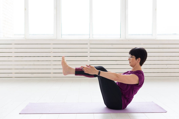 Yoga, conceito de pessoas - uma mulher de meia-idade fazendo um ioga e tentar fazer um asana
 - Foto, Imagem
