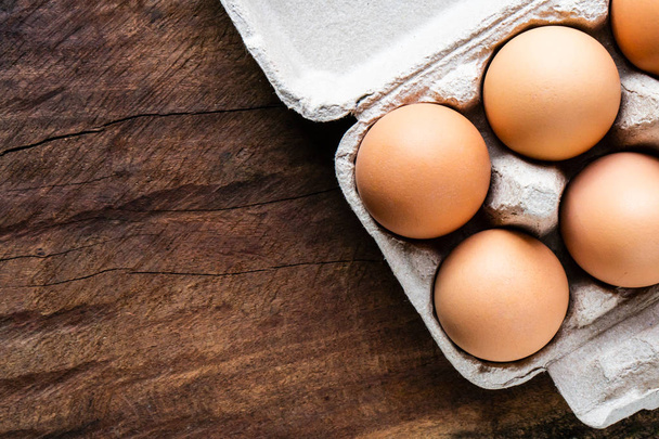 生の鶏の卵、そこの平面図は、割れを防ぐためきちんと整理箱に配置されます。すべての料理を待機する茶色の木製のテーブル上に配置. - 写真・画像