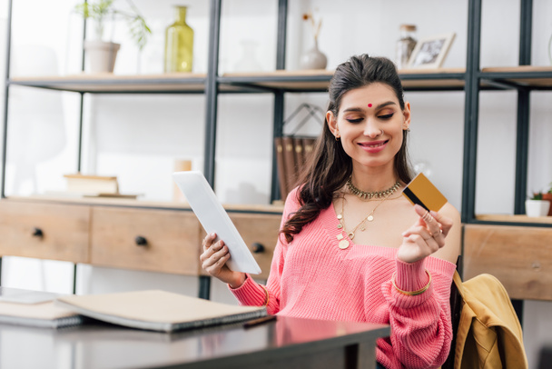 улыбающаяся индианка с планшетом в руках бинди и кредитной картой
 - Фото, изображение