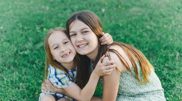 two cute sisters having fun together outdoors and hugging - Photo, image