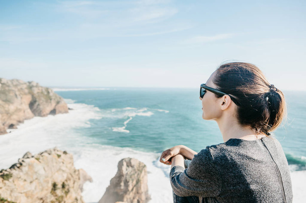 A menina no topo do penhasco em solidão admira a bela vista do Oceano Atlântico
 - Foto, Imagem