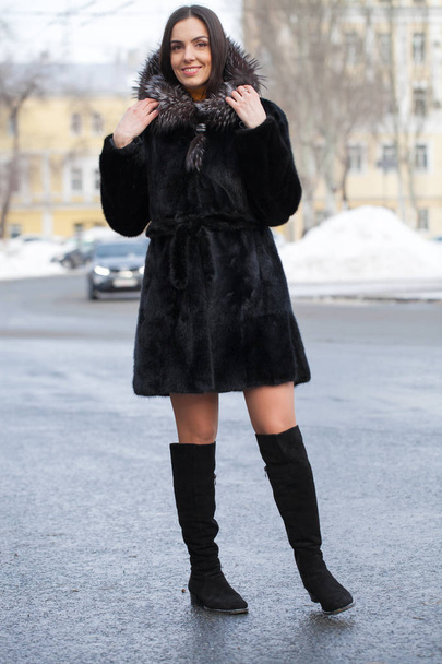 Full body. Young beautiful brunette woman in fur mink coat posing on winter park. Model wearing stylish warm clothes. - 写真・画像