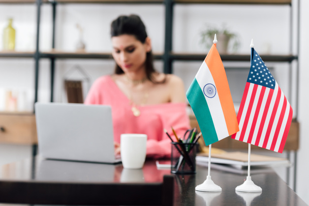 selective focus of american and indian flags on table and girl studying with laptop - Фото, зображення