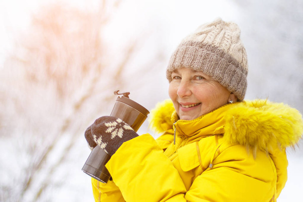 Dorosły Kobieta w żółtym zimowym płaszczu ciesząc się kawą w dniu zimowym.  - Zdjęcie, obraz