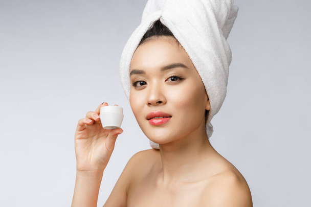 concepto de salud y belleza - Mujer asiática atractiva aplicando crema en su piel, aislado en blanco
. - Foto, imagen