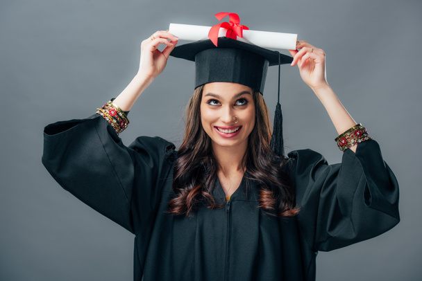 neşeli Hint öğrenci mezuniyet şapkalı diploma, gri izole holding - Fotoğraf, Görsel