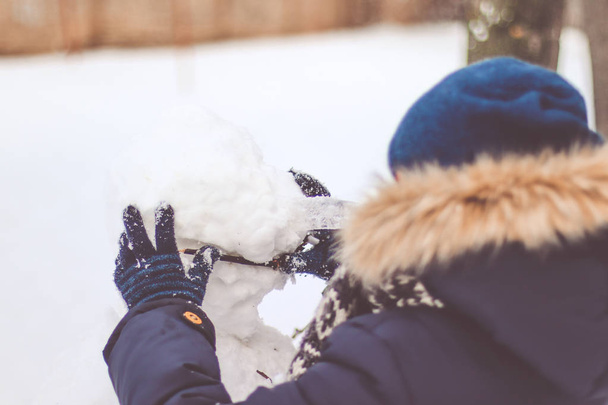  A gyermek sculpts egy hóember. - Fotó, kép