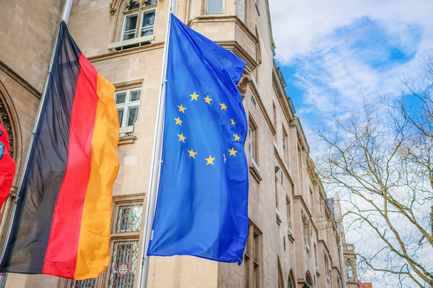 Bandiera verticale dell'Unione europea e bandiera della Germania sullo sfondo della città tedesca
 - Foto, immagini