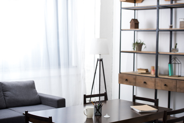 пустая гостиная со столом, диваном, лампой и полками
  - Фото, изображение