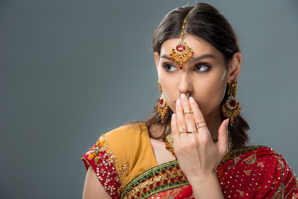 σοκαρισμένος ελκυστική ινδική γυναίκα κλείνει το στόμα, απομονώνονται σε γκρι  - Φωτογραφία, εικόνα