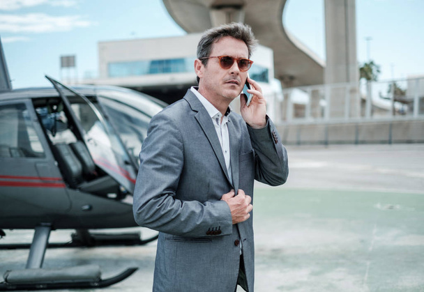 Businessman standing near private helicopter - Foto, Imagen