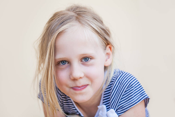 Schattig klein meisje in blauwe jurk consumptiemelk en glimlachend buitenshuis - Foto, afbeelding