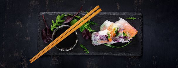 Vegetarian vietnamese spring rolls with spicy sauce, carrot, cucumber, red cabbage and rice noodle. Vegan food. Tasty meal.  Top view, flat lay, banner - Foto, afbeelding