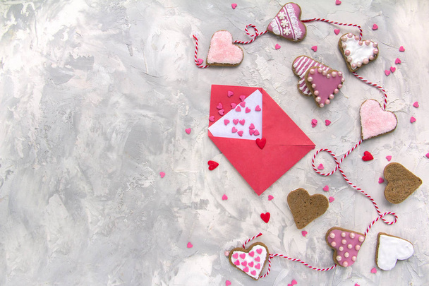 A letter paper for Valentine's day with a hearts, cookies in the shape of a heart, Icing, Red ribbon on Vintage gray texture table Top View Copy Space Gingerbread painting - Valokuva, kuva
