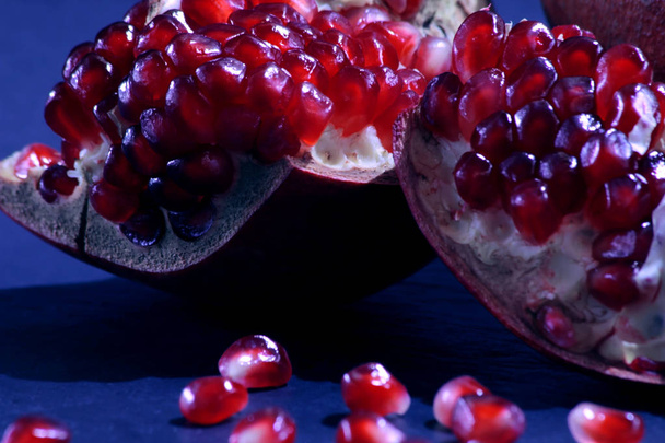 Vörös gránát közelről. gyümölcsdarabokkal, gránátalma, sötét háttér előtt. Élelmiszer-egészségügyi fitness koncepció. - Fotó, kép