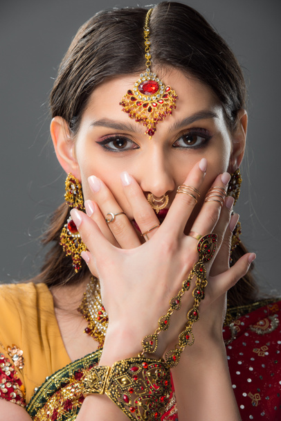 όμορφη ινδική γυναίκα με bindi κλείσιμο πρόσωπο με τα χέρια, απομονώνονται σε γκρι  - Φωτογραφία, εικόνα