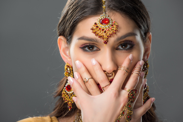attractive indian woman with bindi closing face with hands, isolated on grey  - Valokuva, kuva