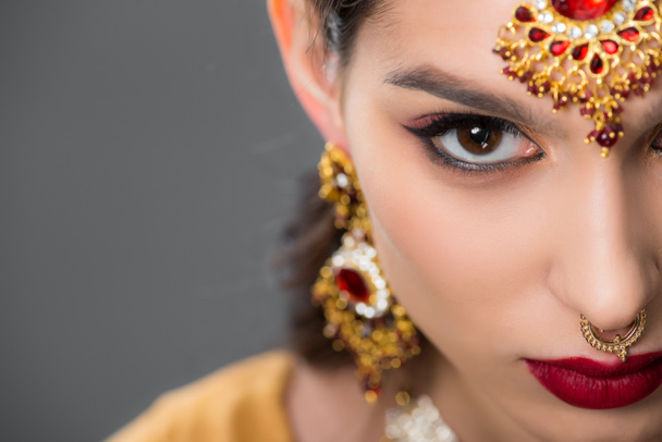 Close up van Indiase vrouw poseren in traditionele accessoires, geïsoleerd op grijs  - Foto, afbeelding