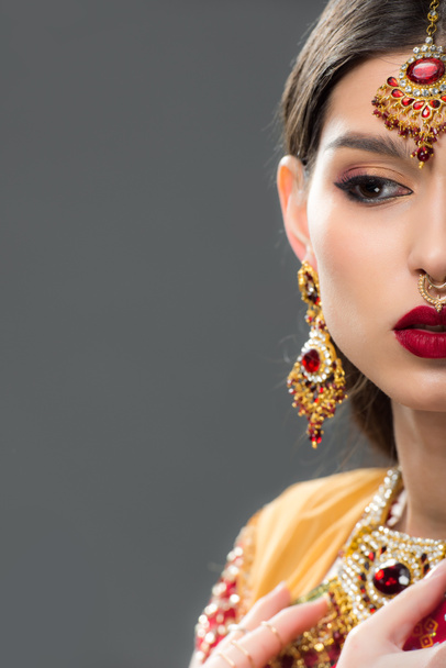 half view of attractive indian woman in sari and accessories, isolated on grey  - Photo, Image