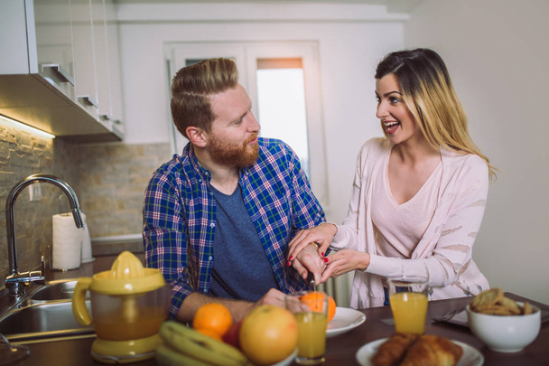 Glückliches Paar macht Orangensaft in der Morgenküche und amüsiert sich.  - Foto, Bild