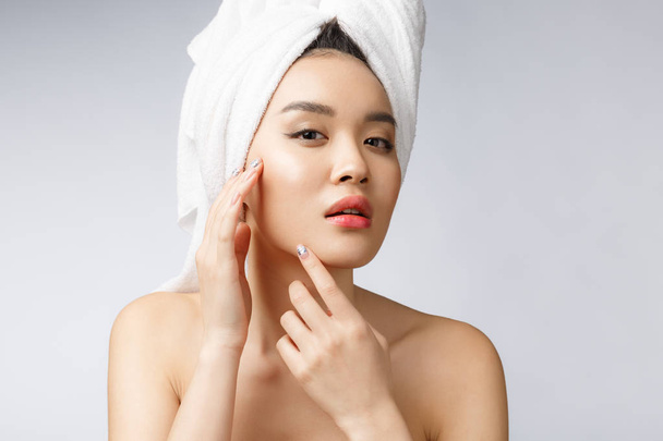 Mujer asiática mirando grano en la cara. La joven intenta quitarse la espinilla. Concepto de cuidado de la piel mujer. Aislado sobre fondo blanco
 - Foto, imagen
