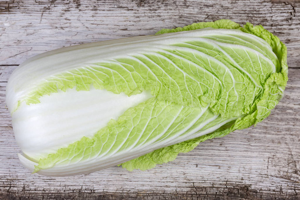 Top view of whole head of napa cabbage also known as chinese cabbage on an old cracked wooden surface - Photo, Image