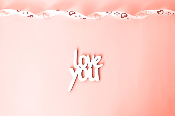 A szó szeretlek, a korall háttér, fehér szalaggal. Valentin-nap. Szent Valentin-nap. - Fotó, kép