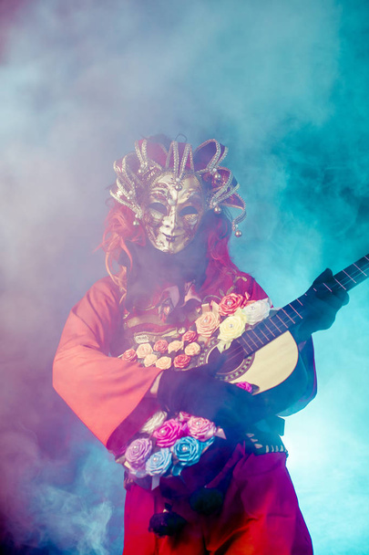 carnival man in venetian costume and mask posing with guitar against misty background - Foto, Imagem