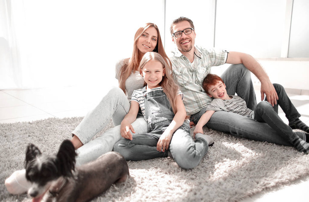 happy family with pet sitting on the carpet - Foto, imagen