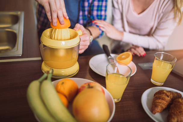 Ζευγάρι κάνει χυμό πορτοκάλι το πρωί κουζίνα, κοντινό πλάνο. - Φωτογραφία, εικόνα
