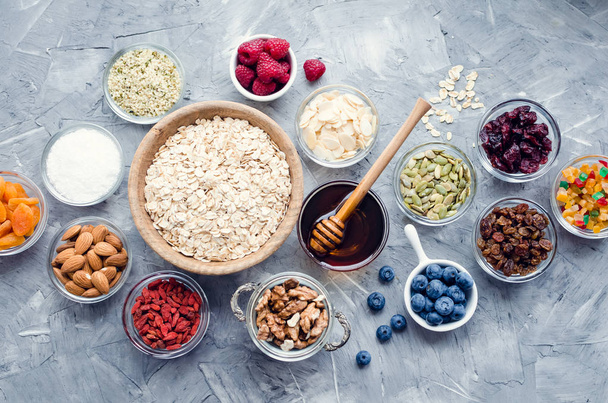 Ingredients for homemade granola: oats, chia, hemp and pumpkin seeds, cranberries and almonds, coconut and agave nectar, goji berries and raisins, dates and apricots. Superfood. Top view. Flat lay. - Fotoğraf, Görsel
