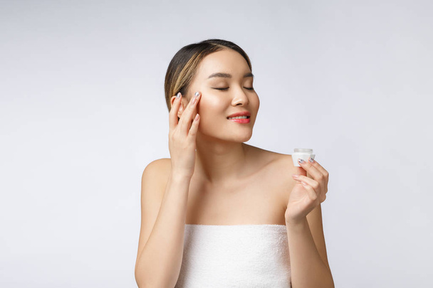 Aasialainen nainen soveltamalla kosmeettinen kerma iholla eristetty valkoinen tausta - Valokuva, kuva