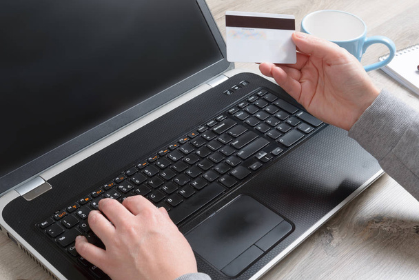 Mão de mulher segurando cartão de crédito sobre notebook e usá-lo para pagar on-line com ele, conceito de e-commers e pagamento online
 - Foto, Imagem
