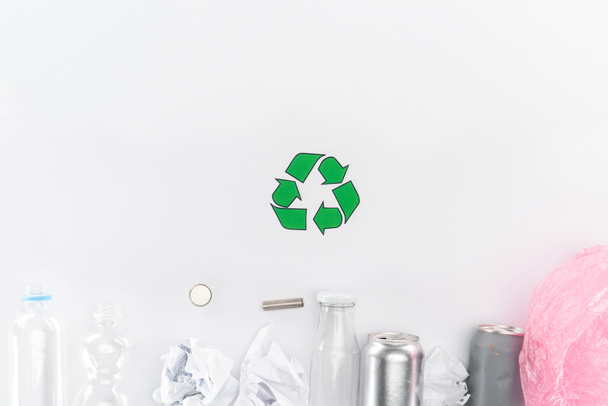 Vista superior de latas, botellas de plástico y vidrio, baterías, papel, signo de reciclaje y bolsa de plástico rosa
 - Foto, Imagen