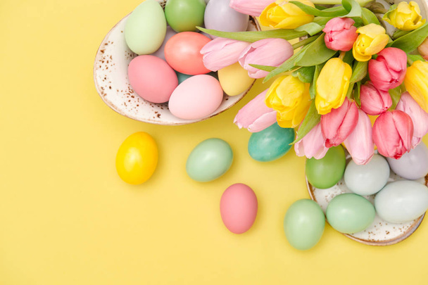 Easter eggs decoration and pastel colored tulip flowers on yellow background - Zdjęcie, obraz