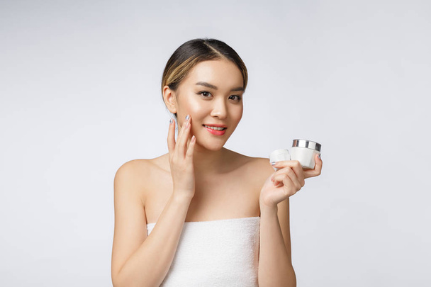Femme asiatique appliquant la crème cosmétique sur la peau sur fond blanc isolé - Photo, image
