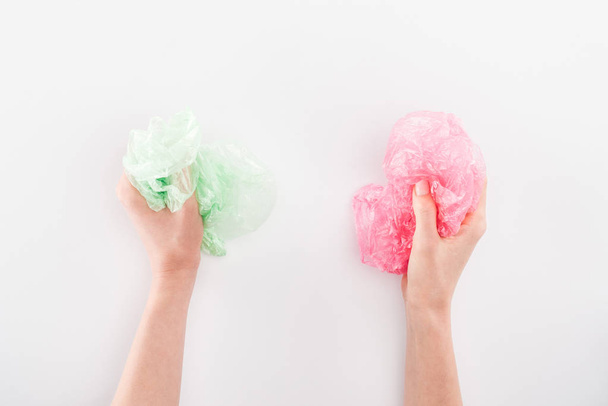 Cropped view of woman holding pink and green plastic bags on grey background - Foto, immagini