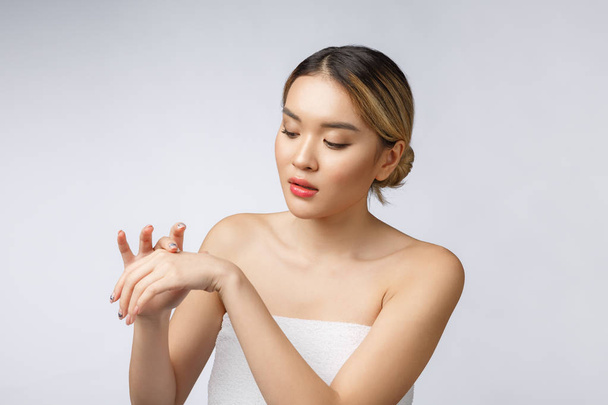 Ασιάτισσα γυναίκα εφαρμογή καλλυντική κρέμα στο δέρμα σε απομονωμένο λευκό φόντο - Φωτογραφία, εικόνα