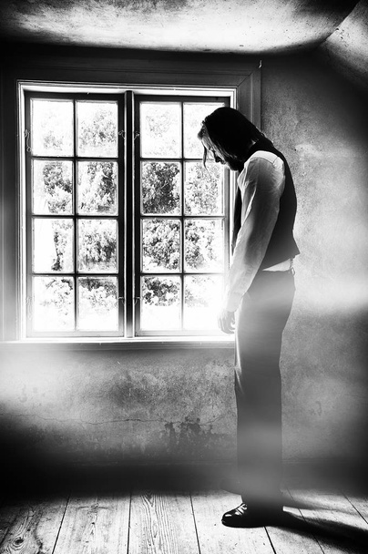 Creative black and white textured image of sad man in front of a window. - Photo, Image